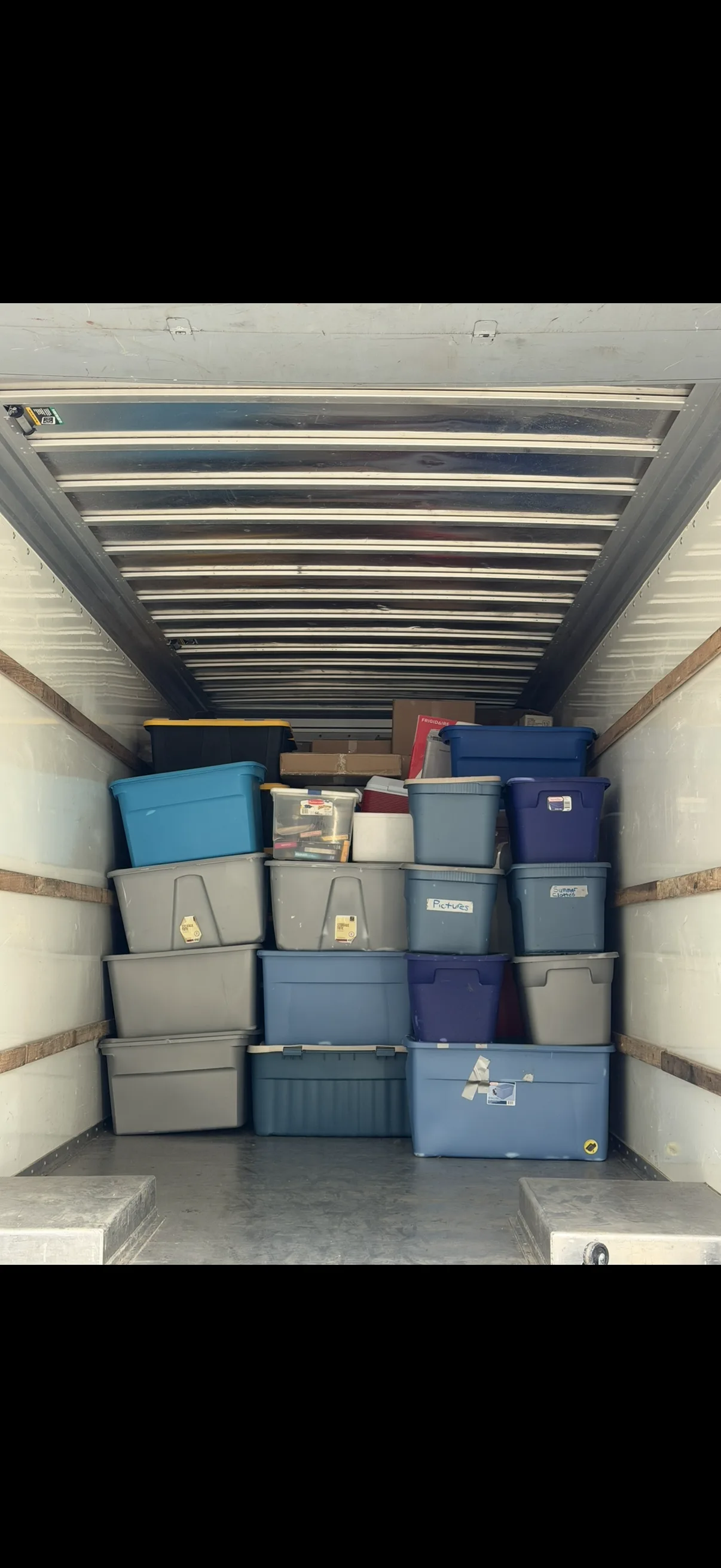 Moving truck interior with color-coded storage bins neatly strapped